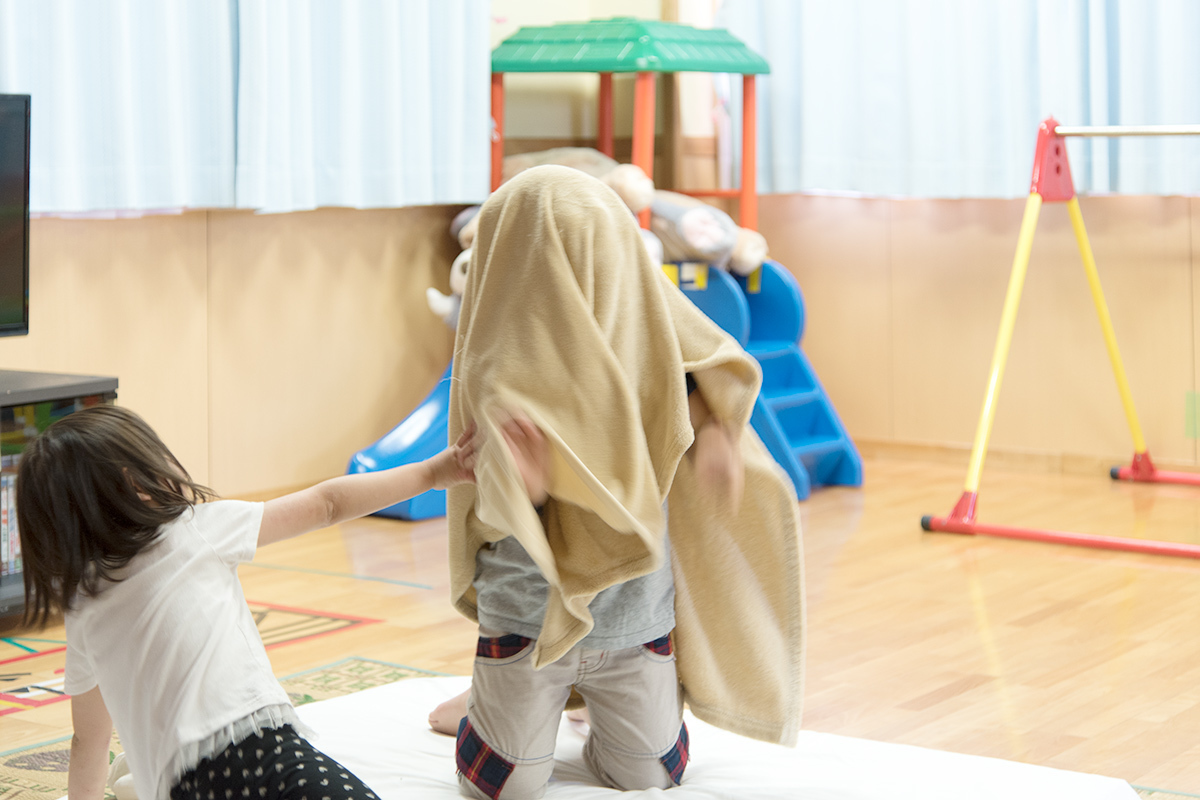 毛布をかぶって遊ぶ子供たち